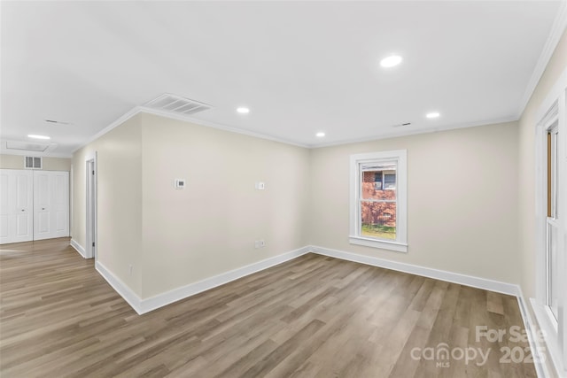 empty room with ornamental molding and light hardwood / wood-style floors