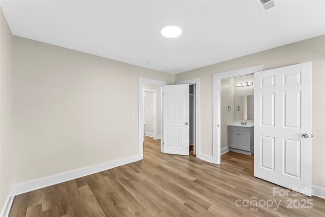 unfurnished bedroom featuring light wood-type flooring, sink, and connected bathroom