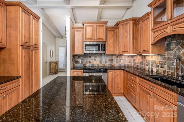 kitchen with stainless steel appliances, backsplash, dark stone counters, and sink