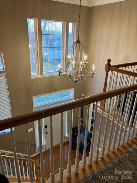 staircase with hardwood / wood-style floors and a notable chandelier