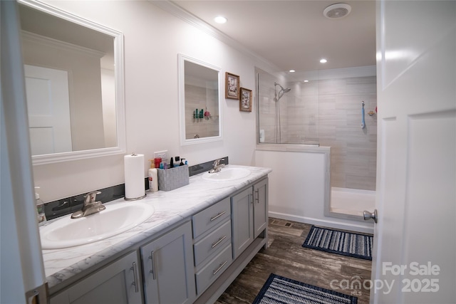 bathroom featuring a tile shower, vanity, ornamental molding, and hardwood / wood-style flooring