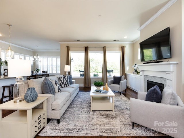 living room with a premium fireplace, a healthy amount of sunlight, hardwood / wood-style floors, and crown molding