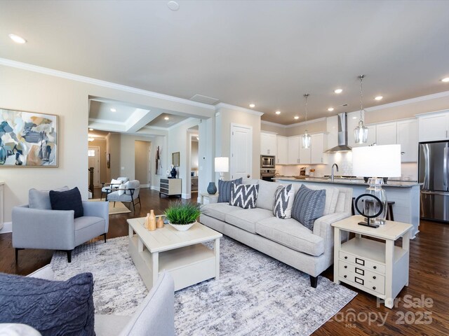 living room featuring ornamental molding, sink, and hardwood / wood-style floors