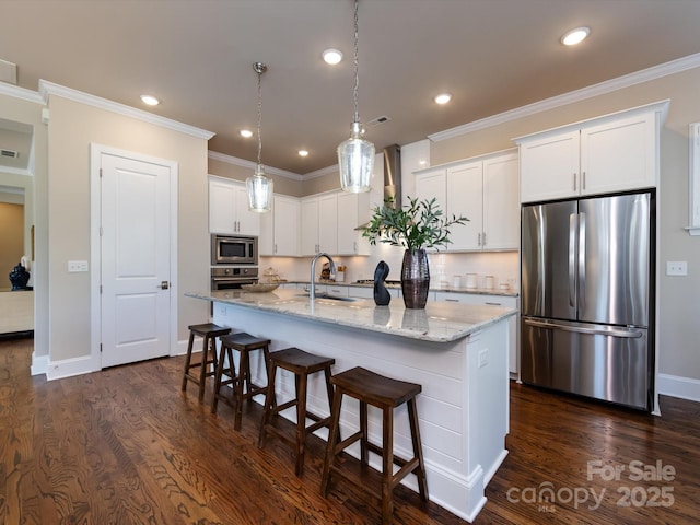 kitchen with a breakfast bar, white cabinetry, stainless steel appliances, light stone countertops, and a center island with sink