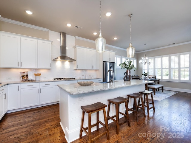 kitchen with white cabinetry, wall chimney exhaust hood, and a kitchen island with sink