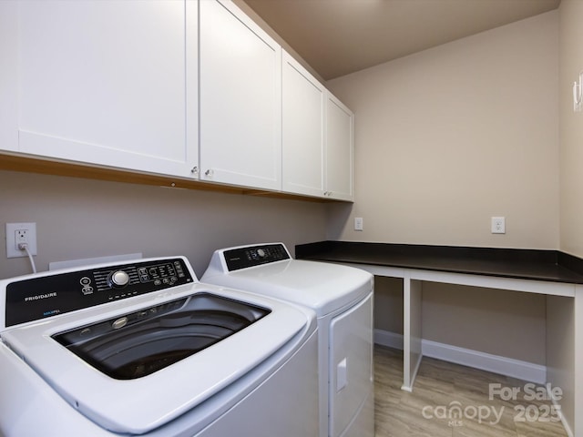 clothes washing area featuring cabinets, washing machine and clothes dryer, and light hardwood / wood-style floors