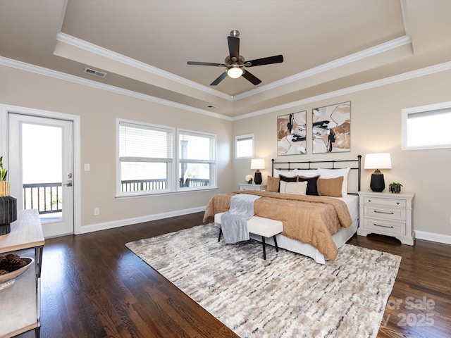 bedroom with dark hardwood / wood-style floors, a tray ceiling, and multiple windows