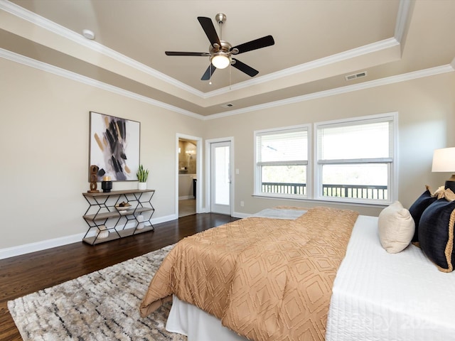 bedroom with dark wood-type flooring, ceiling fan, a tray ceiling, and crown molding