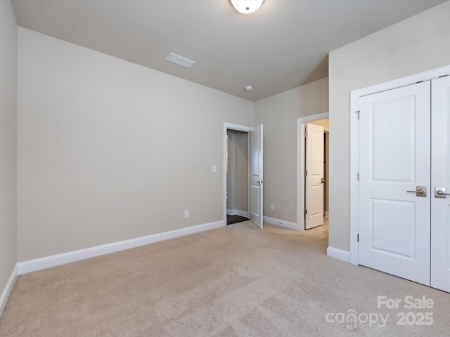 unfurnished bedroom featuring light colored carpet and a closet