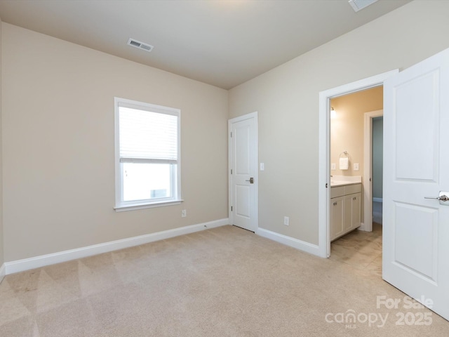 unfurnished bedroom featuring light carpet and ensuite bathroom