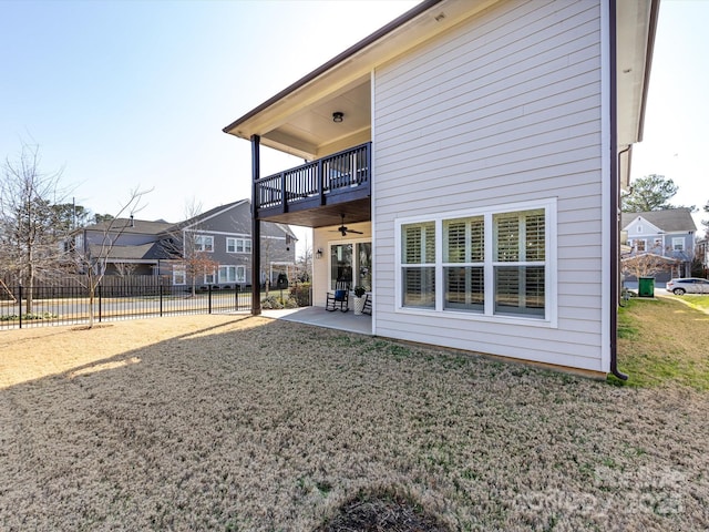 back of house with ceiling fan, a patio area, a balcony, and a lawn