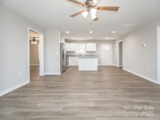 kitchen featuring white cabinets, a center island, stainless steel appliances, ceiling fan, and light hardwood / wood-style flooring