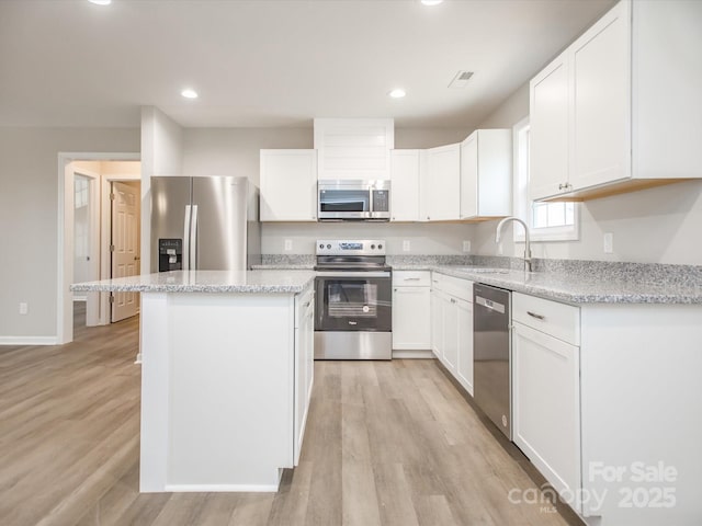 kitchen featuring white cabinets, appliances with stainless steel finishes, a center island, and sink