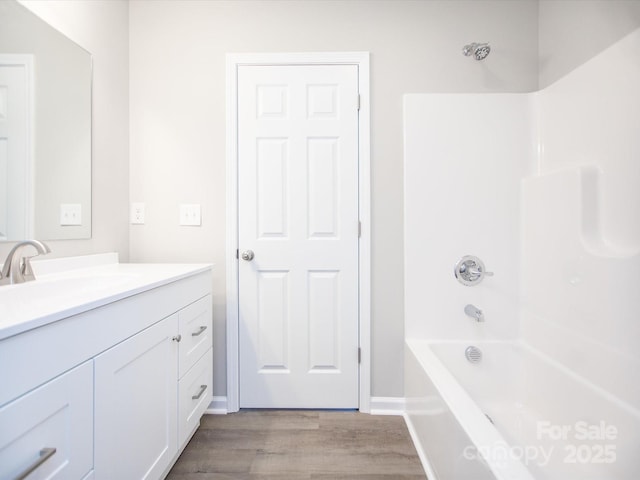 bathroom featuring washtub / shower combination, wood-type flooring, and vanity