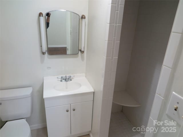 bathroom featuring toilet, vanity, and tiled shower