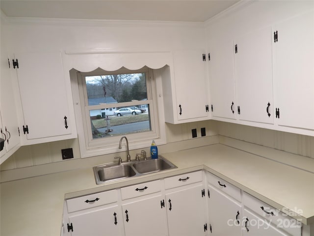 kitchen with white cabinetry, light countertops, and a sink