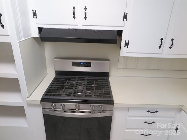 interior details featuring white cabinets, stainless steel gas range oven, light countertops, and under cabinet range hood