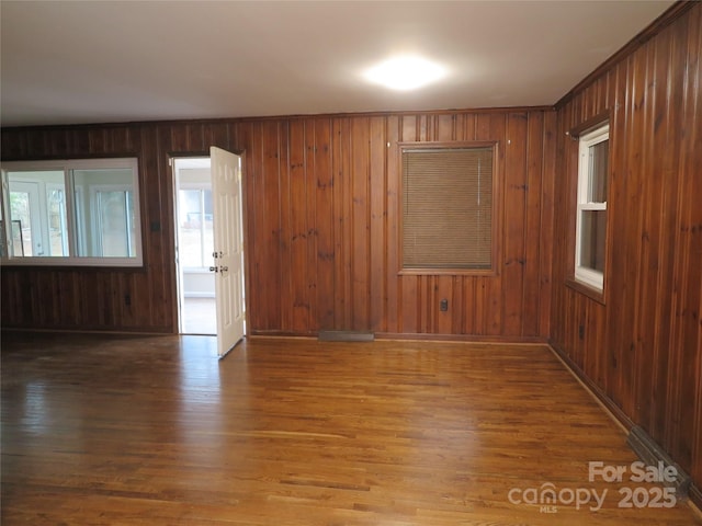spare room featuring wood finished floors and wood walls
