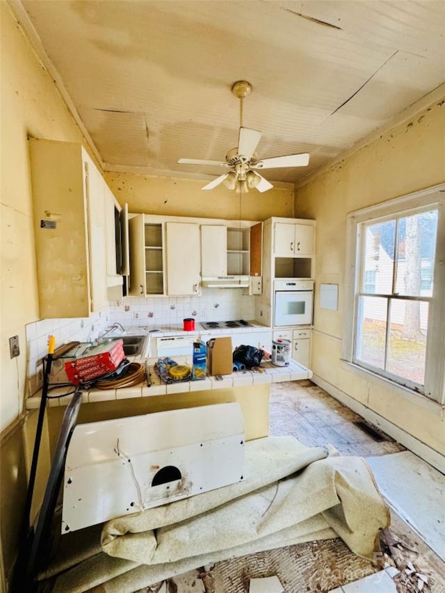 kitchen with white appliances, tile counters, ceiling fan, decorative backsplash, and white cabinetry