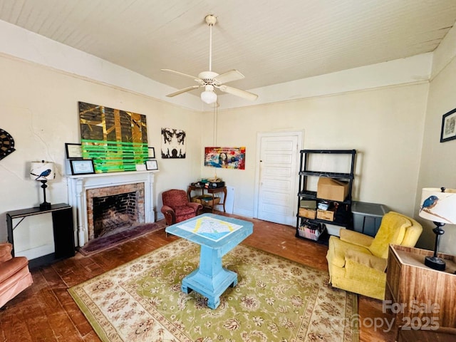 living room featuring ceiling fan, dark wood-type flooring, and a brick fireplace