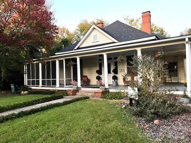 rear view of house featuring a lawn, a porch, and a sunroom