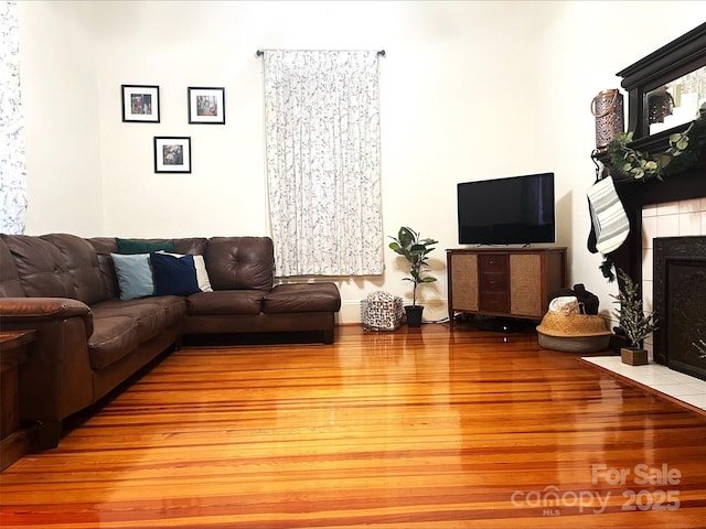 living room featuring light wood-type flooring and a tile fireplace