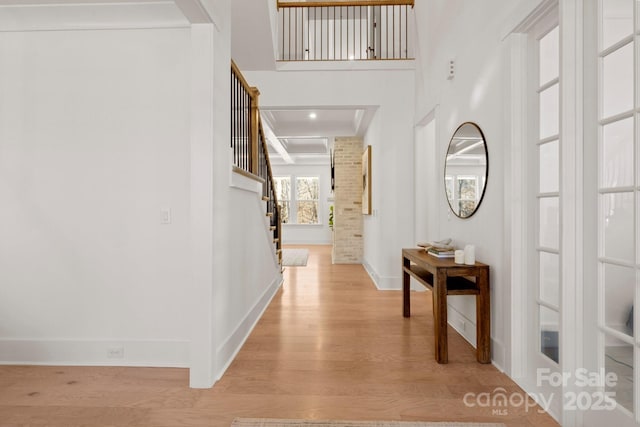 hallway featuring stairs, light wood-type flooring, and baseboards