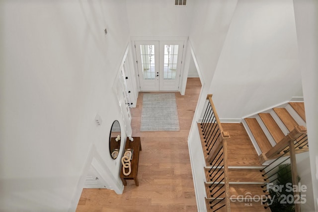 foyer entrance with french doors, light wood finished floors, visible vents, stairway, and baseboards