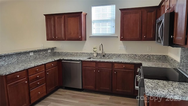 kitchen featuring sink, light stone counters, stainless steel appliances, and light hardwood / wood-style floors