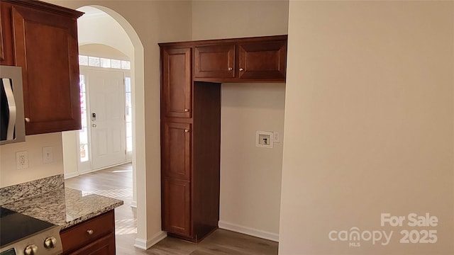 kitchen featuring wood-type flooring, light stone countertops, a wealth of natural light, and stainless steel range