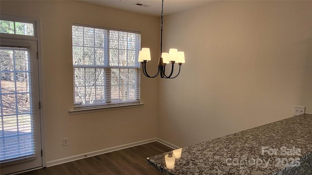 dining space featuring dark wood-type flooring, plenty of natural light, and an inviting chandelier