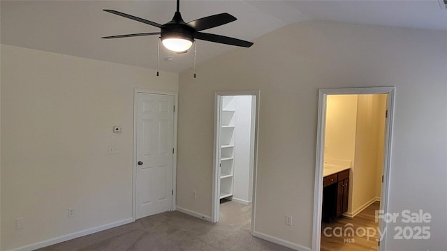 unfurnished bedroom featuring ceiling fan, lofted ceiling, a spacious closet, connected bathroom, and a closet