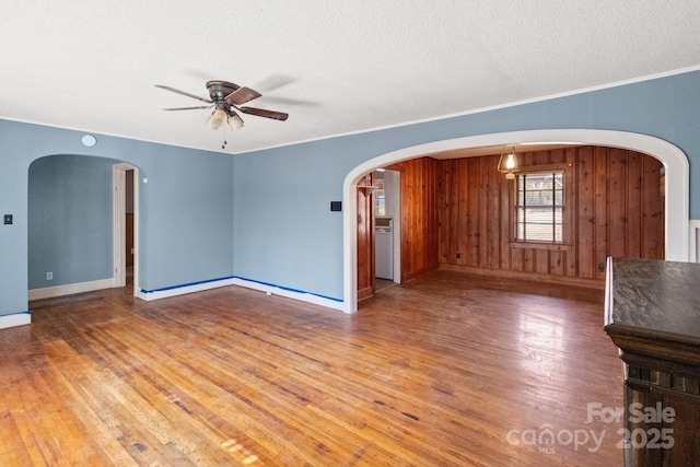 interior space featuring ceiling fan, wood-type flooring, wooden walls, and a textured ceiling