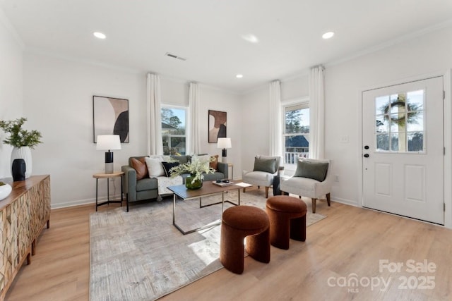 living area with ornamental molding and light hardwood / wood-style flooring