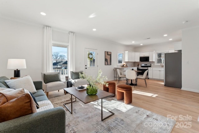 living room with ornamental molding and light hardwood / wood-style flooring