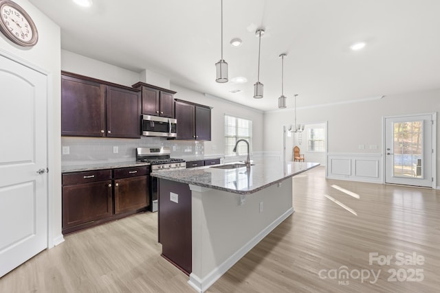 kitchen with stone counters, pendant lighting, an island with sink, a breakfast bar area, and stainless steel appliances