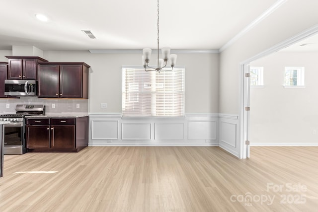 kitchen with hanging light fixtures, light wood-type flooring, stainless steel appliances, ornamental molding, and a chandelier