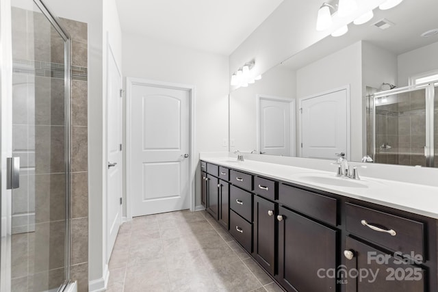 bathroom with a shower with shower door, vanity, and tile patterned floors