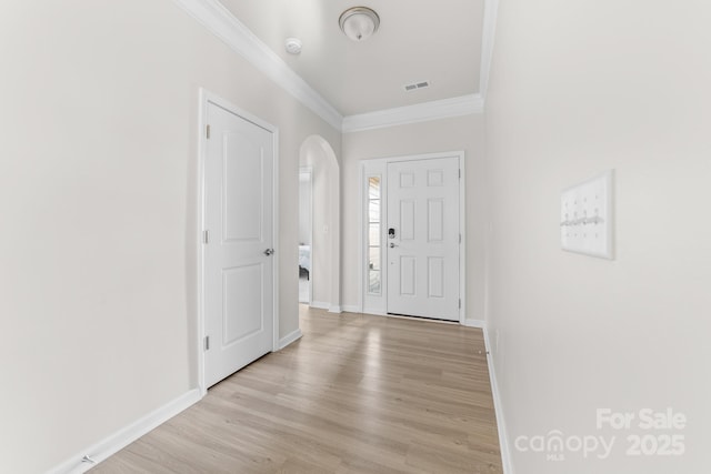 foyer with ornamental molding and light hardwood / wood-style floors