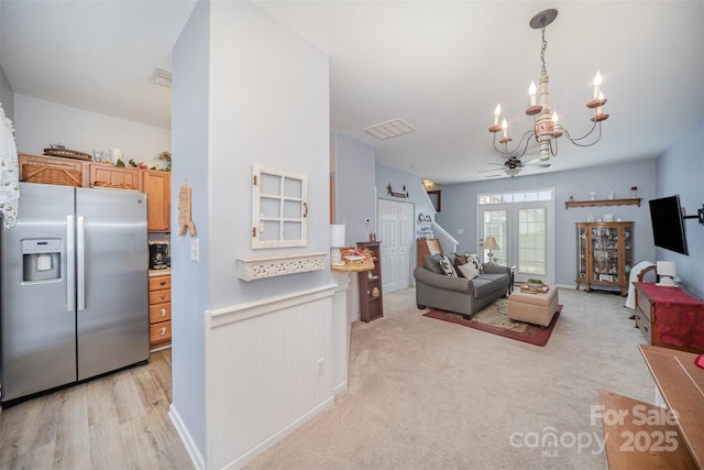 living room with light wood-type flooring and ceiling fan with notable chandelier