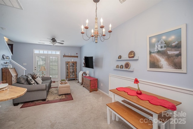 carpeted living room featuring ceiling fan with notable chandelier