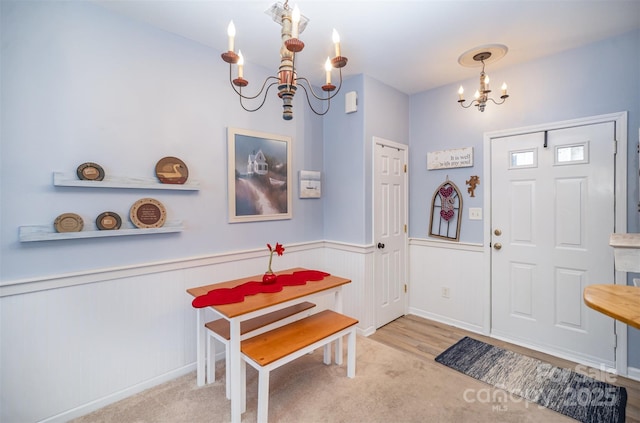 foyer featuring light colored carpet and a notable chandelier