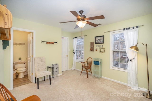 sitting room with ceiling fan, light colored carpet, and a healthy amount of sunlight