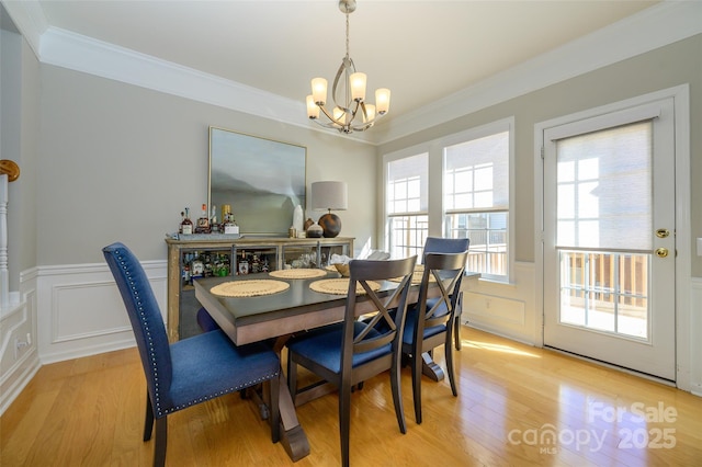 dining space with an inviting chandelier, a wealth of natural light, light hardwood / wood-style floors, and ornamental molding