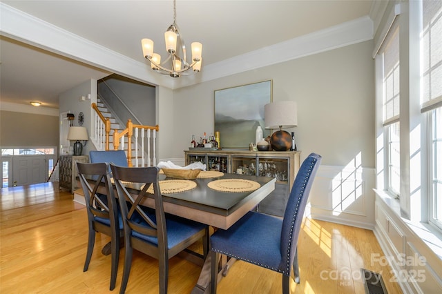 dining area with light hardwood / wood-style flooring, ornamental molding, and a notable chandelier