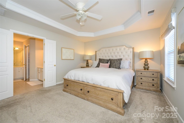 carpeted bedroom with a raised ceiling, ensuite bath, ceiling fan, and crown molding