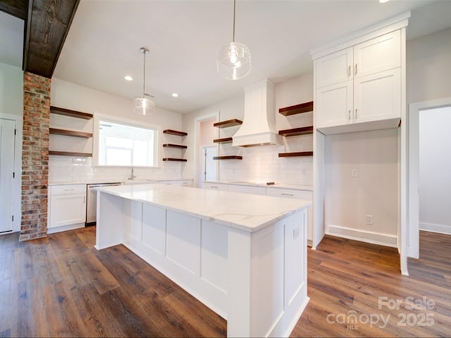 kitchen featuring white cabinetry, decorative light fixtures, dishwasher, custom range hood, and light stone counters