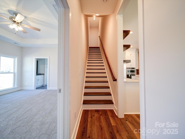 staircase with ceiling fan and wood-type flooring