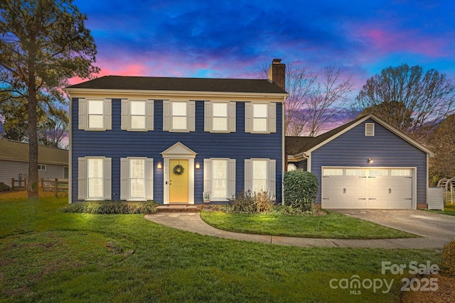 colonial inspired home with a garage and a yard