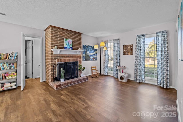 interior space with dark wood-type flooring, a brick fireplace, and a textured ceiling